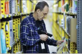  ?? THE ASSOCIATED PRESS ?? A clerk picks an item from a shelf Wednesday and scans it with a hand-held device to fill a customer order at the Amazon Prime warehouse in New York.