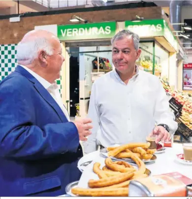  ?? M. G. ?? Jesús Aguirre y José Luis Sanz toman churros en un puesto del mercado de Pino Montano.