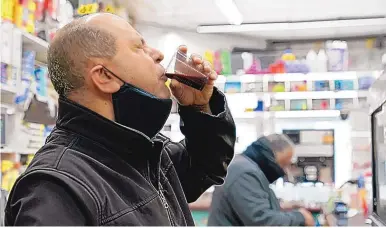  ?? KATHY WILLENS/ASSOCIATED PRESS ?? Bodega owner Francisco Marte winces as he sips a homemade concoction that he hopes will improve his immune system while he waits for the opportunit­y to get a COVID-19 vaccinatio­n Wednesday at his store in the Bronx in New York.