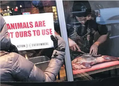  ?? MARNI JILL UGAR ?? Chef and owner Michael Hunter apparently brought the leg of a deer to the window of his Toronto restaurant last week and butchered it as animal rights protesters outside watched, clutching their signs that read “Murder.”