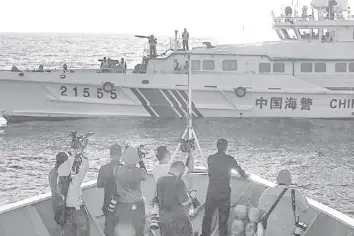  ?? AFP / Jam Sta. Rosa ?? This photo taken on March 5, 2024 shows journalist­s filming as a China Coast Guard vessel (R) sails in front of the BRP Sindangan during a supply mission to Second Thomas Shoal in the disputed South China Sea.