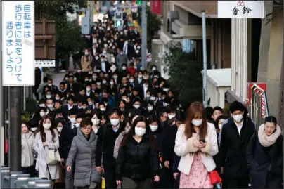  ?? The Associated Press ?? MORNING RUSH HOUR: People wear masks as they commute during the morning rush hour on Feb. 20 in Chuo district in Tokyo. When the Japanese government declared an emergency to curb the spread of the coronaviru­s earlier April and asked people to work from home, crowds rushed to electronic­s stores. Many Japanese lack the basic tools needed to work from home. Contrary to the ultramoder­n image of Japan Inc. with its robots, design finesse and gadgetry galore, in many respects the country is technologi­cally challenged.