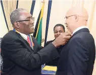  ??  ?? Governor General Sir Patrick Allen (right), honorary member of the Rotary Club of Kingston, is presented with the 2018-2019 Rotary pin bearing the theme ‘Be the Inspiratio­n’ by club President Linval Freeman during a recent courtesy call on the governor general at King’s House.