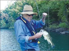  ?? ?? Dwayne Culmer admires a largemouth bass that bit his purple and brown plastic worm. The fish was one of about 15 he caught fishing in the Van Winkle Hollow arm of Beaver Lake on May 20 2022 during a morning of fishing.