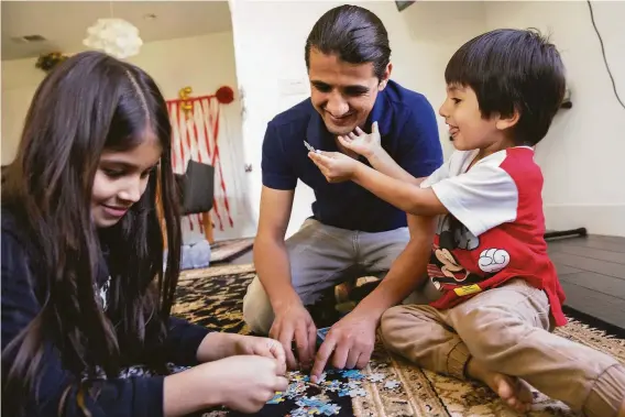  ?? Jessica Christian / The Chronicle ?? Mr. Sultani spends time playing with Uzma (left) and Edris. The family, who live in Milpitas, had traveled to Afghanista­n in June to visit a sick relative.