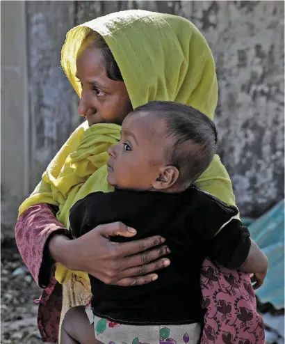  ?? Photo: Reuters/Marko Djurica. Inset, Aung San Suu Kyi ?? A Rohingya refugee woman holds her child after they crossed the Myanmar-Bangladesh border on Christmas Day.