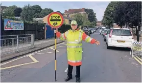  ?? FOTO: DPA ?? Joe Byrne passt als Lollipop-mann vor der Schule auf, dass alle sicher über die Straße kommen.