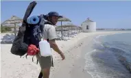  ??  ?? Sous la canicule, un homme marche seul pour nettoyer les plages