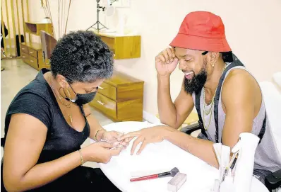  ?? PHOTOS BY SHEREITA GRIZZLE ?? Kimberley Burke, nail technician at EC Makeup Bar, gives owner Matthew ‘Esco Da Shocker’ Thompson a manicure.
