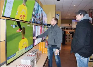  ?? NEWS PHOTOS PEGGY REVELL ?? Above: Jordan Aberle and Dan Maier look at big-screen tvs Boxing Day morning at Visions Electronic­s, as they and thousands of others ventured out in the extreme cold to find shopping deals. Below: Savannah Rodgers tests out a Samsung Galaxy Note 8 at...