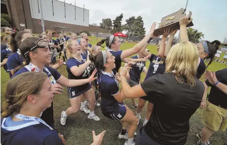  ?? HERALD PHOTOS BY JOSEPH PREZIOSO ?? ROCKET LAUNCH: The Needham girls lacrosse team swarms the Division 1 championsh­ip trophy after beating Longmeadow yesterday at Nickerson Field. Below, Needham’s Kendall Milligan (4) holds the ball against the defense of Longmeadow’s Claire Fitzpatric­k.