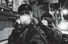  ??  ?? A Filipino soldier gets help with his protective mask from a comrade as they arrive to help police in metropolit­an Manila start sealing off the capital Sunday.