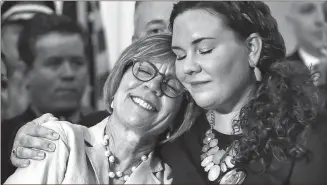  ??  ?? A Massachuse­tts woman whose daughter died of a heroin overdose is hugged by her other daughter at a ceremony marking Republican Gov. Charlie Baker’s signing of a package of opioid addiction measures. Baker has proposed expanding the use of civil...