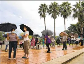  ?? Lynne Sladky Associated Press ?? EARLY VOTERS line up on a rainy Monday in Miami. President Trump and Democratic nominee Joe Biden are both relying heavily on Florida’s Latino voters.