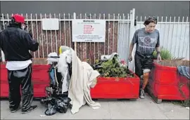  ?? Gary Coronado Los Angeles Times ?? RED PLANTER BOXES and a warning sign don’t fully succeed in keeping homeless people away from the Hungarian Cultural Alliance on Hope Street.