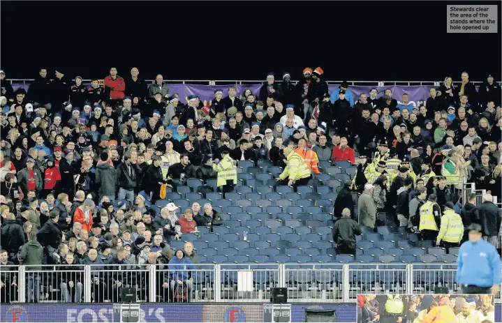  ??  ?? Stewards clear the area of the stands where the hole opened up