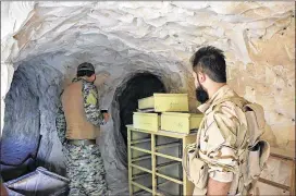  ?? SYRIAN ARAB NEWS AGENCY ?? Syrian troops and pro-government gunmen stand inside a cave Saturday that they seized from Islamic State militants in the eastern city of Deir el-Zour, Syria. The city has been divided into government- and IS-controlled parts since 2015.