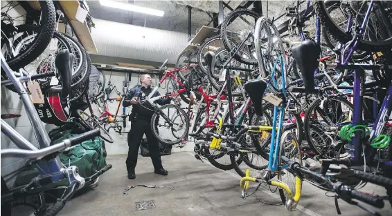  ??  ?? Const. Sean Millard, who runs the Victoria Police Department bike registry, places a bicycle in the seized-bike locker at police headquarte­rs on Caledonia Avenue. Police are urging cyclists to register their bikes to combat “opportunit­y-seeking...