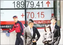  ?? (AP) ?? People stand in front of an electronic stock board of a securities firm in Tokyo, on April 3. Asian markets were mostly higher Monday, cheered by a positive report on the Japanese economy, as players awaited a meeting
between US and Chinese leader...