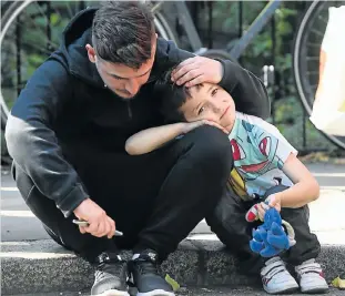  ?? Picture: REUTERS ?? TIME TO RECOVER: A man comforts a boy after the tower block was severely damaged by a serious fire