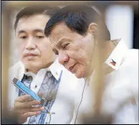  ??  ?? President Duterte takes a call from US President Donald Trump on the sidelines of a gala dinner for leaders of the Associatio­n of Southeast Asian Nations at the Sofitel Hotel in Pasay City on Saturday night. Holding the phone for Duterte is...
