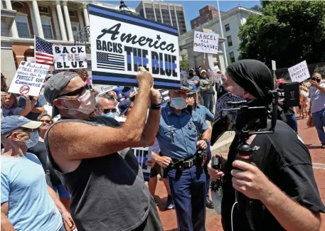  ?? MATT sTonE pHoTos / HErAld sTAFF ?? CURIOUS STANDOFF: Rod Webber, right, heckles pro-police supporters during a rally in front of the State House on Thursday. Below left, State Police try to intercede in an argument between protesters.