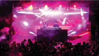  ??  ?? A deejay (DJ) mixes tracks as youths attend an electronic dance music event, during the annual Baghdad Summer Festival at the People’s Hall in the Iraqi capital. — AFP photos