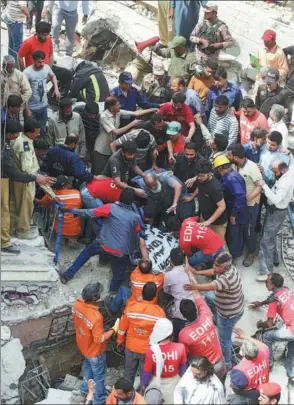  ??  ?? Pakistani volunteers remove the body of a victim from the rubble of a three-story residentia­l building in Karachi on Monday. At least two people were killed and others were wounded after the building collapsed while under constructi­on.