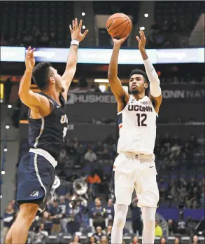  ?? Jessica Hill / Associated Press ?? UConn’s Tyler Polley (12) shoots as New Hampshire’s Mark Carbone (5) defends during a game last season in Hartford.