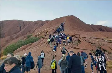  ?? — Reuters ?? Drawing in the crowd: Tourists crowding a trail as they attempt to climb Uluru in this image obtained from social media.