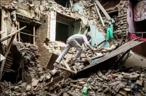  ?? Omar Havana/Getty Images ?? A man climbs on top of collapsed buildings Sunday in Bhaktapur, Nepal, a day after parts of the nation were devastated by a 7.8 -magnitude earthquake.