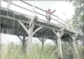  ?? GARETH FULLER — PA VIA AP ?? Silke Lohmann of Summers Place Auctions stands on the original Poohsticks Bridge from Ashdown Forest, featured in A.A. Milne’s Winnie the Pooh books and E.H. Shepard’s illustrati­ons.