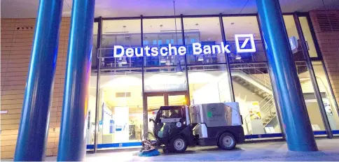  ??  ?? A road cleaning machine drives past the exterior of a Deutsche Bank bank branch in Berlin on Sept 28, 2016. WP-Bloomberg photo