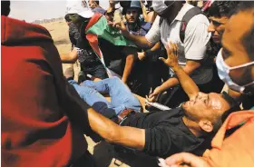  ?? Spencer Platt / Getty Images ?? A Palestinia­n man is rushed to an ambulance at the border fence. Gaza’s Hamas rulers say the protests will continue until the Israeli blockade is lifted.