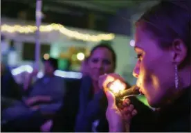  ?? BRENNAN LINSLEY — THE ASSOCIATED PRESS FILE ?? Rachel Schaefer, of Denver, smokes marijuana on the official opening night of Club 64, a marijuana-specific social club, where a New Year’s Eve party was held in Denver.