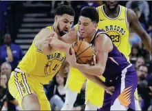  ?? AP ?? Phoenix Suns’ Devin Booker tries to maintain possession while driving past Golden State Warriors guard Klay Thompson during Sunday’s NBA game in Oakland, California.