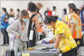  ?? Marco Garcia The Associated Press ?? A traveler is assisted by a state official Thursday at Daniel K. Inouye Internatio­nal Airport in Honolulu. A new pre-travel testing program allows visitors who test negative for COVID-19 to come to Hawaii and avoid two weeks of mandatory quarantine.