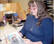  ?? PAT HARRIS ENTERPRISE-LEADER ?? Dianna Payne, library director, looks over a book as she sits at the Lincoln Public Library desk. Payne has loved reading since she read author Laura Ingalls Wilder books.