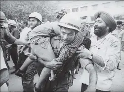  ?? PRAKASH SINGH/HT ARCHIVE ?? A police official rushes a victim to the hospital.