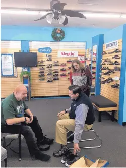  ??  ?? Peg Swisher and sales associate Jim Matteucci, right, consult with customer Peter Kalitsis to find property fitting shoes.