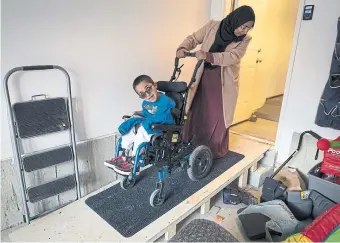  ?? PETER POWER FOR THE TORONTO STAR ?? Khadija Zafar helps her son into their home in Waterdown using a ramp in the garage. The family has been on the subsidized accessible-housing wait-list since she was pregnant with her son.