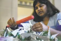  ??  ?? Volunteer Pranitha Polsani of Nissan Technologi­es uses a flat iron to straighten origami cranes so they can be hung.