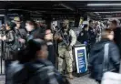 ?? Photograph: Justin Lane/ EPA ?? New York state police officers and national guard troops monitor an entrance to the transit system.