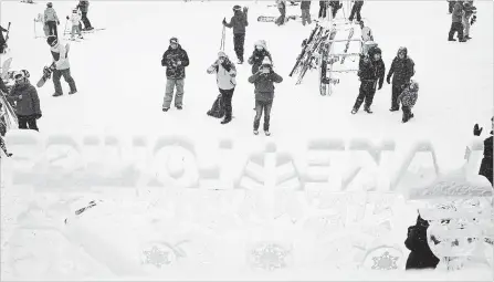  ?? JEFF MCINTOSH THE CANADIAN PRESS ?? Tourists photograph an ice sculpture as heavy snow falls at the Lake Louise ski resort