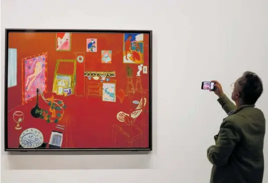  ?? MOHAMMED BADRA (EFE) / JEAN-LOUIS LOSI ?? Un visitante fotografia­ba el día 3 El taller rojo (1911), de Matisse, expuesto en la Fundación Louis Vuitton, en París. Abajo, la escultura Nu debout, dos cambré (1906-1907), en una imagen de los herederos del artista.