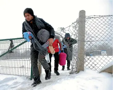  ?? AP ?? Migrants walk through the snow at the Lipa camp, northwest Bosnia, near the border with Croatia. Hundreds of migrants are stranded in the burnt-out camp as heavy snow fell and temperatur­es dropped during a winter spell of bad weather after fire earlier this week destroyed much of the camp.