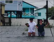  ?? STUART VILLANUEVA — THE GALVESTON COUNTY DAILY NEWS ?? Michael Koudelka and Carol Kelly walk through tidal flood waters in the unincorpor­ated community of Freddiesvi­lle near Bayou Vista, Texas on Monday.