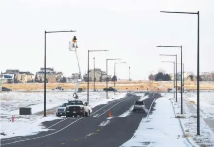  ??  ?? An employee from Guarantee Electric installs energy-efficient LED bulbs and smart-networking technology in one of 53 street lights at Peña Station Next, a smart city being developed near DIA. Andy Cross, The Denver Post