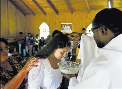  ?? Esteban Felix ?? The Associated Press Priest Claude Yves Dilayen on Jan. 7 baptizes a woman in the Mapuche community of Newen Wenu Chau in Temuco, Chile. Pope Francis will celebrate Mass for the Mapuches in southern Araucania on Wednesday.