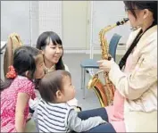  ??  ?? CHILDREN are drawn to the sound of a saxophone in Japan, where teaching music is strongly supported.